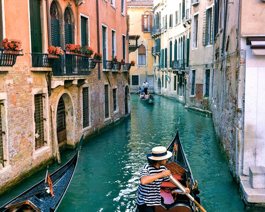 A gondolier floating down the Venice canals with flower boxes in the windows. Discover 15 picture perfect reasons to visit Italy. And for more travel tips and wanderlust inspiration follow The Scenic Suitcase on Pinterest!