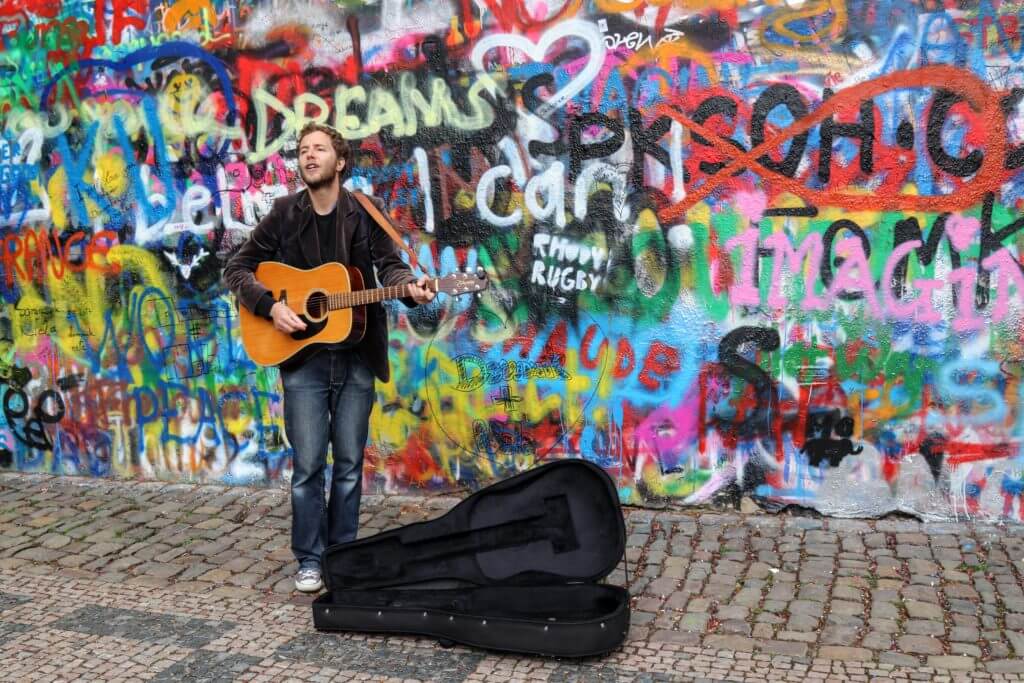 The musician playing a guitar at the John Lennon Wall. Discover 25 picture perfect reasons to visit Prague, Czech Republic. Want even more wanderlust inspiration? Follow The Scenic Suitcase on Pinterest!