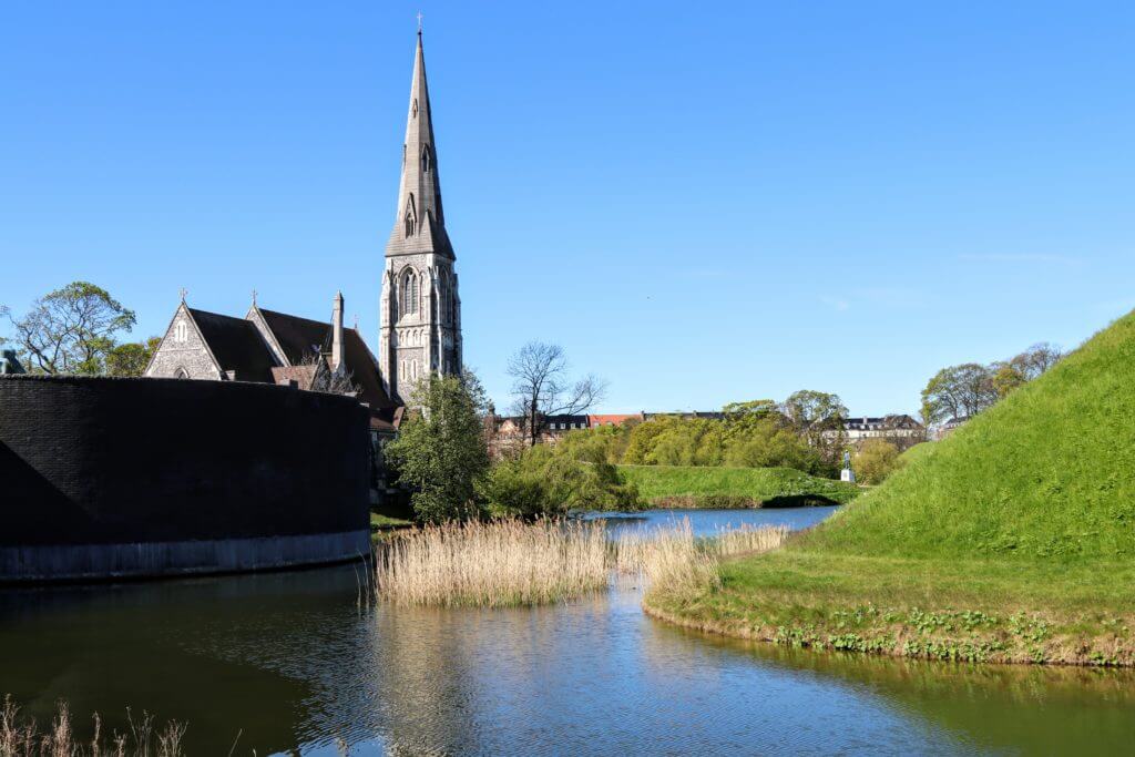 A church and mote outside Kastellet. Discover 12 picture perfect reasons to visit Copenhagen, Denmark. Want even more wanderlust inspiration? Follow The Scenic Suitcase on Pinterest!