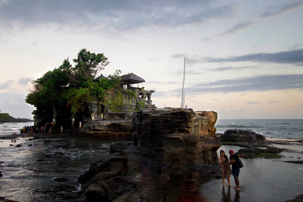 Tanah Lot temple surrounded by the ocean. Discover 27 picture perfect things to see in Bali, Indonesia. And for more travel tips and wanderlust inspiration, follow The Scenic Suitcase on Pinterest!