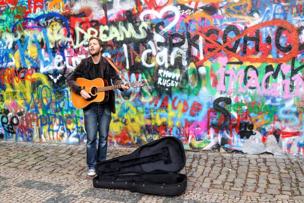 A musician playing the guitar in front of colorful graffiti at the John Lennon Wall in Prague, Czech Republic. Discover the most picture perfect moments of the year. And for more travel tips and wanderlust inspiration, follow The Scenic Suitcase on Pinterest!