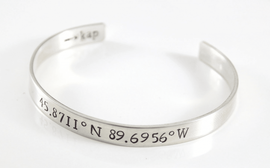 Silver bracelet with latitude and longitude engraved on front.