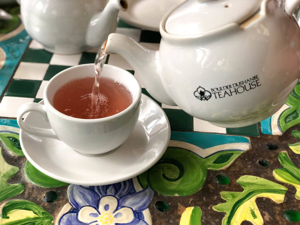 Pouring strawberry tea on an colorful table at the Boulder Dushanbe Teahouse. Discover the fascinating history and stunning beauty of the Boulder Dushanbe Teahouse. Learn why it's one place in Colorado you simply can't miss! And for more travel tips and wanderlust inpiration follow The Scenic Suitcase on Pinterest!