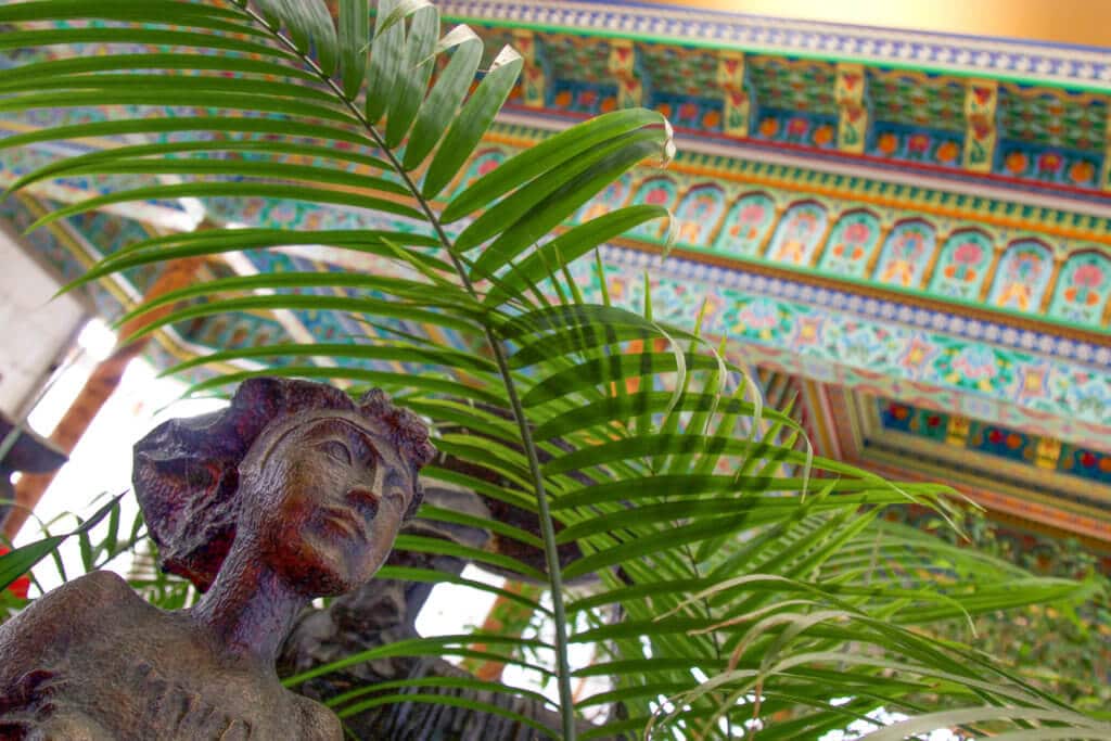 A statue and foliage inside the Boulder Dushanbe Teahouse. Discover the fascinating history and stunning beauty of the Boulder Dushanbe Teahouse. Learn why it's one place in Colorado you simply can't miss! And for more travel tips and wanderlust inpiration follow The Scenic Suitcase on Pinterest!