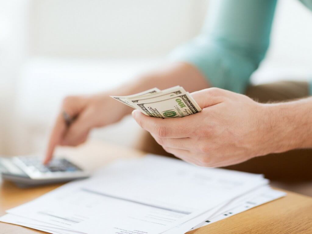 Holding money and using a calculator to pay bills. Discover 6 expert tips on how to save for travel that will help you make your vacation dreams a reality! These proven strategies will allow you to take that trip of a lifetime without taking on debt. For more travel tips and wanderlust inspiration follow The Scenic Suitcase on Pinterest!
