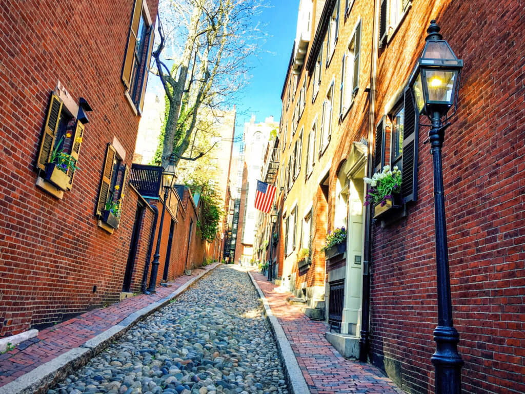 Acorn Street with cobblestones, brick facades, classic street lamps, flower boxes, and an American flag. Discover the picture perfect reasons to visit Boston, Massachusetts. From historic landmarks to local favorites, this is what you shouldn't miss on your trip to Beantown. And for more wanderlust inspiration and travel tips follow The Scenic Suitcase on Pinterest!