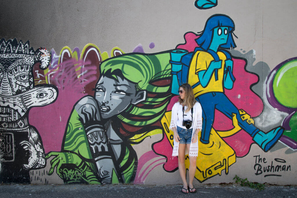 A girl standing by colorful graffiti. Find out why attending The Blonde Abroad photography tour is a once-in-a-lifetime experience you shouldn't miss. And for more travel tips and wanderlust inspiration, follow The Scenic Suitcase on Pinterest!