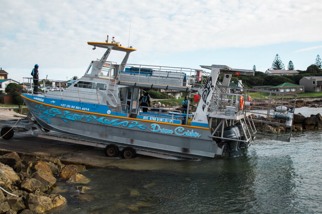 Shark diving boat being lowered into the water. Find out what it's like to go cage diving with great white sharks in South Africa! What to expect, what not to fear, and what company is the best to book your adventure with. And for more travel tips and wanderlust inspiration follow The Scenic Suitcase on Pinterest!