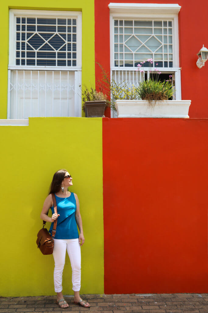 Girl standing next to a yellow and orange building. There are a million reasons to visit South Africa. The country is as diverse as it is beautiful and offers countless activities and bucket list adventures. Find out what you can't miss! And for more travel tips and wanderlust inspiration follow The Scenic Suitcase on Pinterest!
