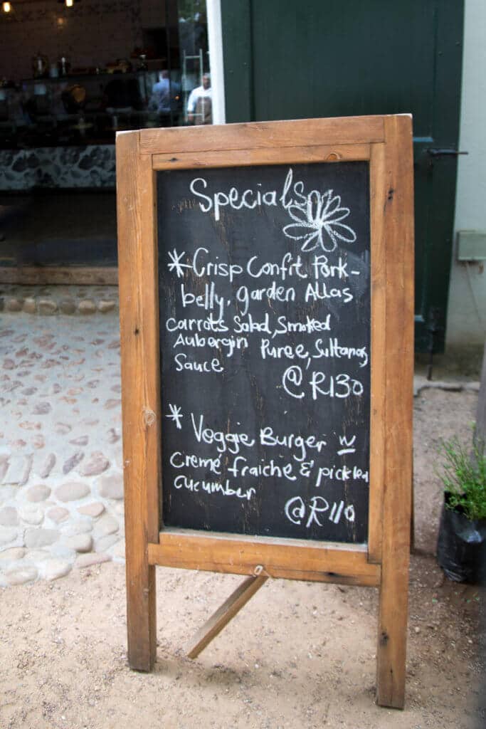 A chalkbard sandwich board with the day's specials written on it. Visiting the Boschendal Wine Farm in South Africa is a treat for the senses. From delectable food to beautiful scenery to the savory wine, it's an experience that shouldn't be missed in South Africa. Here's what you need to know before you go. And for more travel tips and wanderlust inspiration, follow The Scenic Suitcase on Pinterest!