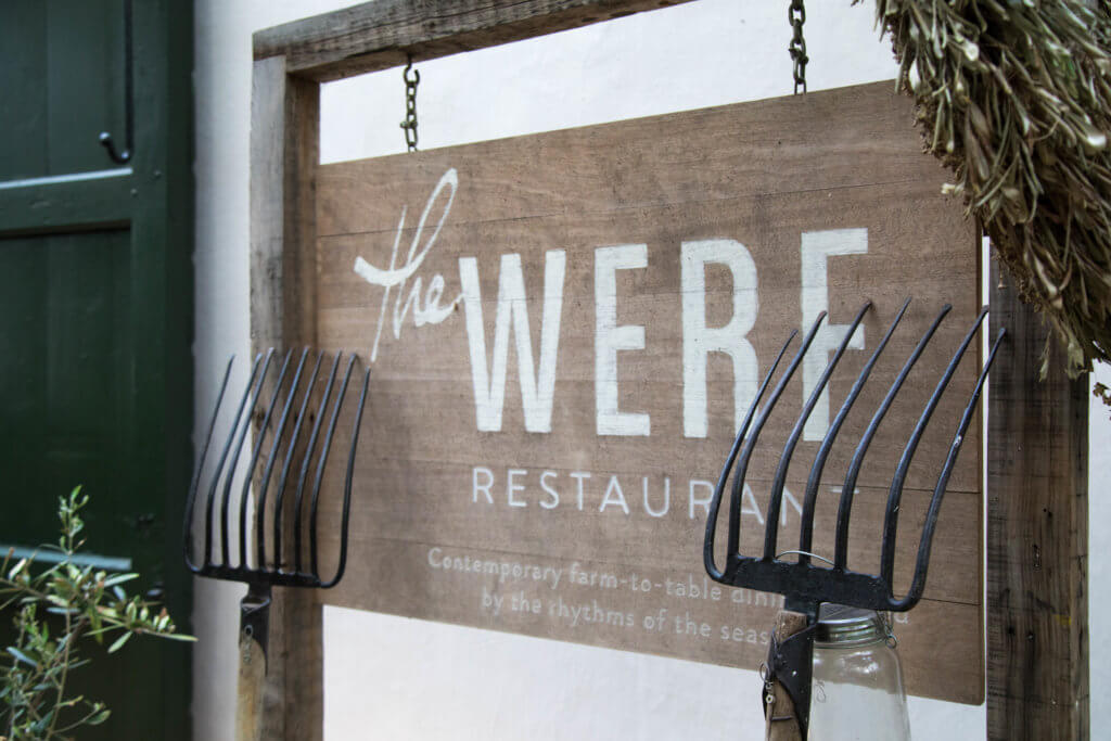 A wooden sign for the Werf restaurant with a pitch fork laying against it. Visiting the Boschendal Wine Farm in South Africa is a treat for the senses. From delectable food to beautiful scenery to the savory wine, it's an experience that shouldn't be missed in South Africa. Here's what you need to know before you go. And for more travel tips and wanderlust inspiration, follow The Scenic Suitcase on Pinterest!