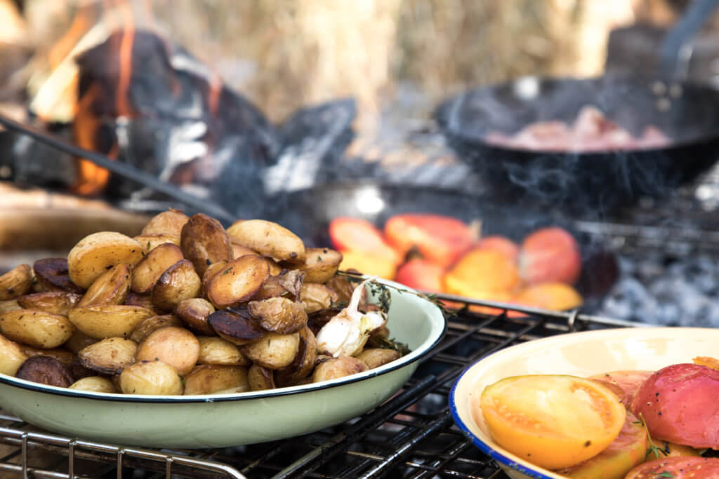 A campfire cooking potatoes and tomatoes. Visiting the Boschendal Wine Farm in South Africa is a treat for the senses. From delectable food to beautiful scenery to the savory wine, it's an experience that shouldn't be missed in South Africa. Here's what you need to know before you go. And for more travel tips and wanderlust inspiration, follow The Scenic Suitcase on Pinterest!