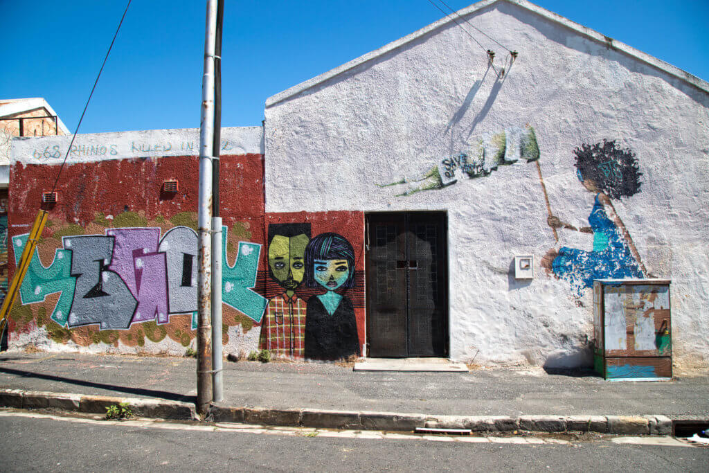 Graffiti art along a street. Discover the unique street art of Woodstock in South Africa. Find out the history behind this eclectic district and why it's a must on any visit to Cape Town! And for more travel tips and wanderlust inspiration follow The Scenic Suitcase on Pinterest!