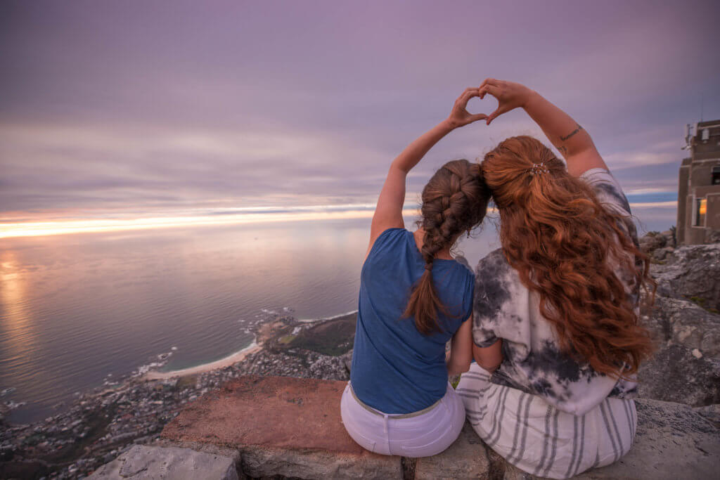 Two girls watching the sunset over the ocean and making a heart with their hands over their heads. There are a million reasons to visit South Africa. The country is as diverse as it is beautiful and offers countless activities and bucket list adventures. Find out what you can't miss! And for more travel tips and wanderlust inspiration follow The Scenic Suitcase on Pinterest!