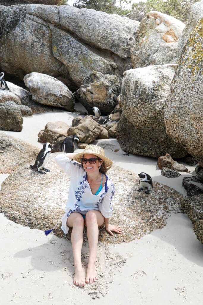 Girl sitting next to penguins on a rock. There are a million reasons to visit South Africa. The country is as diverse as it is beautiful and offers countless activities and bucket list adventures. Find out what you can't miss! And for more travel tips and wanderlust inspiration follow The Scenic Suitcase on Pinterest!