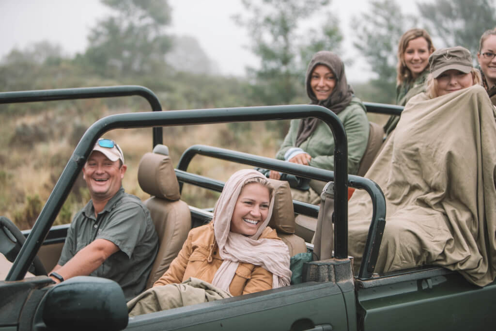 Members of a safari group laughing inside their vehicle.