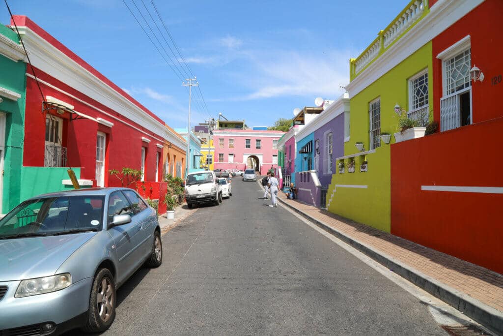 The multi-colored exteriors of the Bo Kaap neighborhood. Visiting Bo Kaap in Cape Town feels like stepping into a cartoon. But there's more to the neighborhood than prismatic facades. Discover the colorful history of one of South Africa's most intriguing communities. Plus, get expert tips on what you need to know before you go! And for more travel tips, follow The Scenic Suitcase on Pinterest!