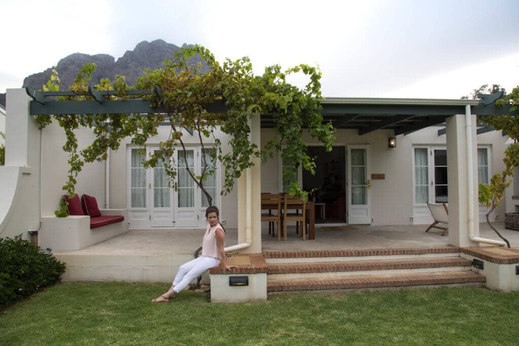 Girl sitting outside a vine covered cottage with a mountain in the background. Visiting the Boschendal Wine Farm in South Africa is a treat for the senses. From delectable food to beautiful scenery to the savory wine, it's an experience that shouldn't be missed in South Africa. Here's what you need to know before you go. And for more travel tips and wanderlust inspiration, follow The Scenic Suitcase on Pinterest!