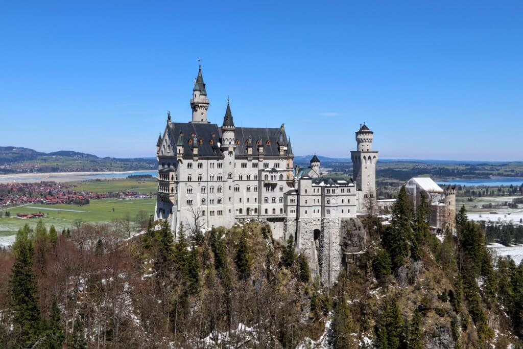 A picture of Neuschwanstein castle with a lake in the background. Trying to figure out how to use a DSLR camera can feel as impossible as trying to figure out how to launch the space shuttle. But it doesn't have to be complicated! Learn the basics of how to stop shooting in auto and start shooting in awesome! And for more travel and photography tips, follow The Scenic Suitcase on Pinterest!