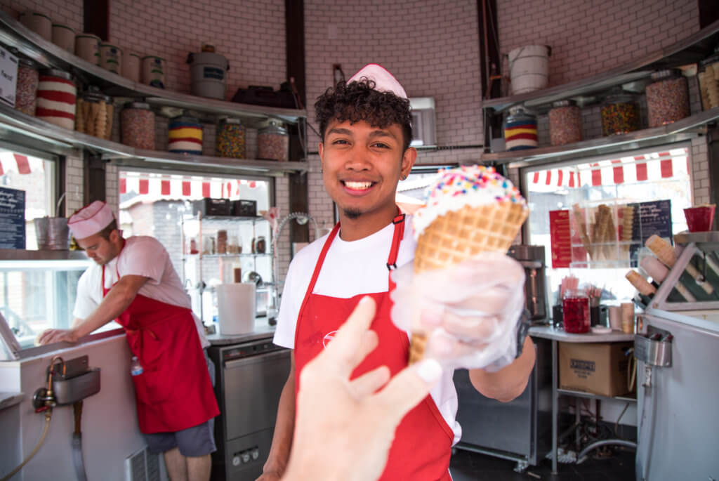A young man with a paper hat serving an ice cream cone with sprinkles. Whether it's the Statue of Liberty, Washington DC, or a quaint hometown parade, these americana images capture the essence of the good ol' U.S.A. And for more travel tips and wanderlust inspiration, follow The Scenic Suitcase on Pinterest!