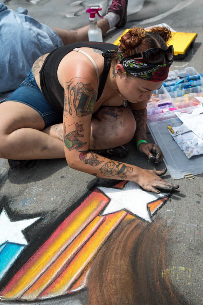 A girl drawing a shooting star in chalk. Find out everything you need to know about the annual Denver Chalk Art Festival! What it's all about, what you can expect, and what you can't miss! And for more travel tips and wanderlust inspiration, follow The Scenic Suitcase on Pinterest!