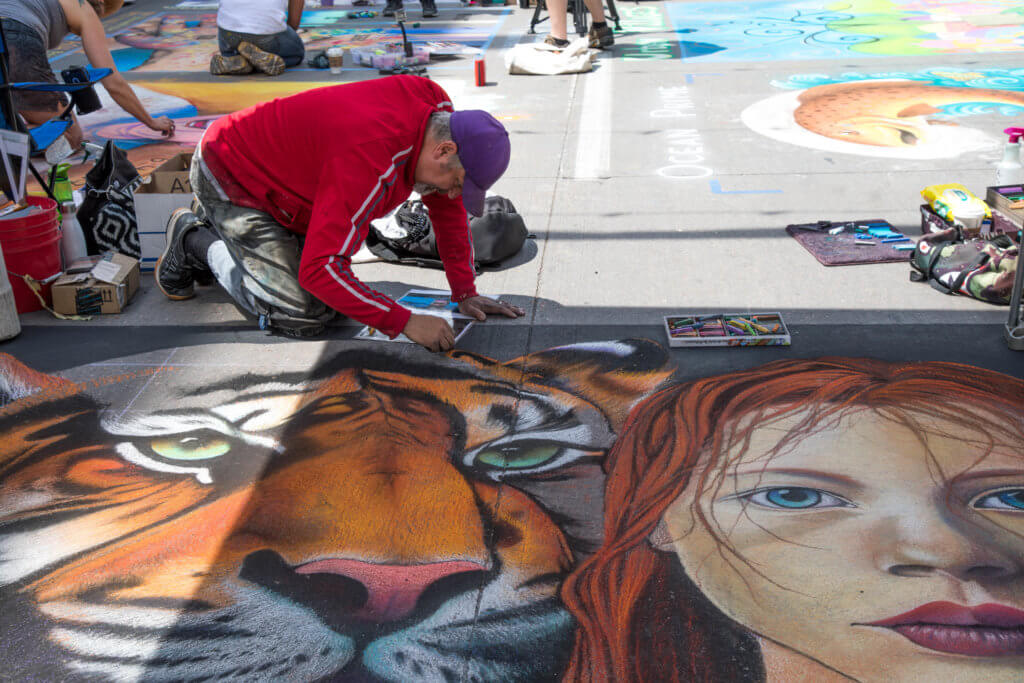 A man drawing a tiger and girl with chalk. Find out everything you need to know about the annual Denver Chalk Art Festival! What it's all about, what you can expect, and what you can't miss! And for more travel tips and wanderlust inspiration, follow The Scenic Suitcase on Pinterest!