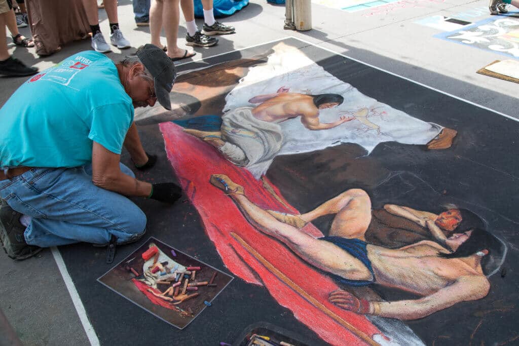 A man drawing a native american with chalk. Find out everything you need to know about the annual Denver Chalk Art Festival! What it's all about, what you can expect, and what you can't miss! And for more travel tips and wanderlust inspiration, follow The Scenic Suitcase on Pinterest!