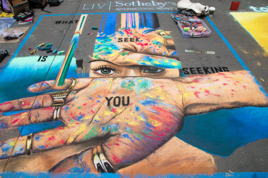 A girl with rainbow paint on her hands drawn with chalk. Find out everything you need to know about the annual Denver Chalk Art Festival! What it's all about, what you can expect, and what you can't miss! And for more travel tips and wanderlust inspiration, follow The Scenic Suitcase on Pinterest!
