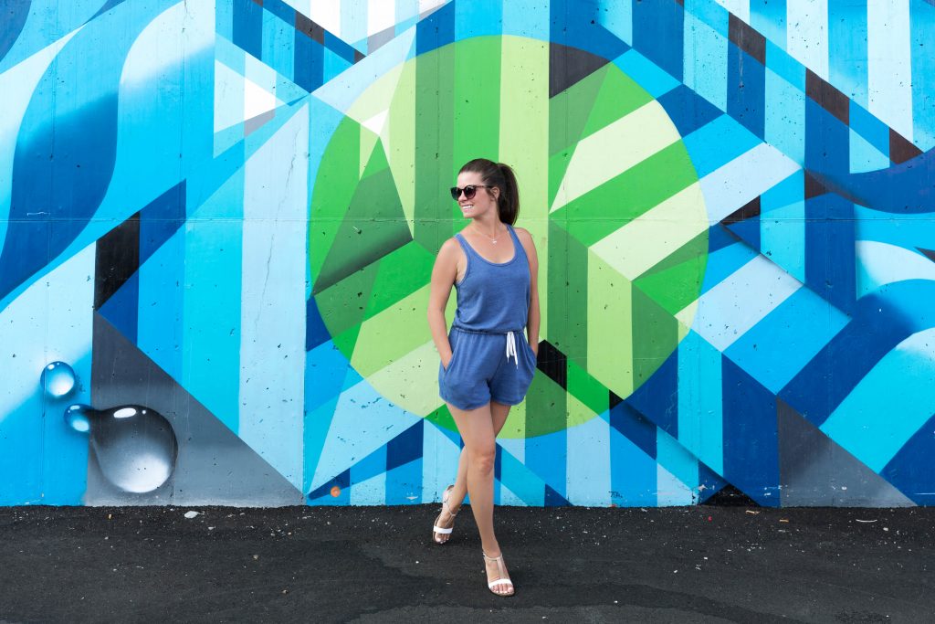 A girl standing next to blue street art in Denver.