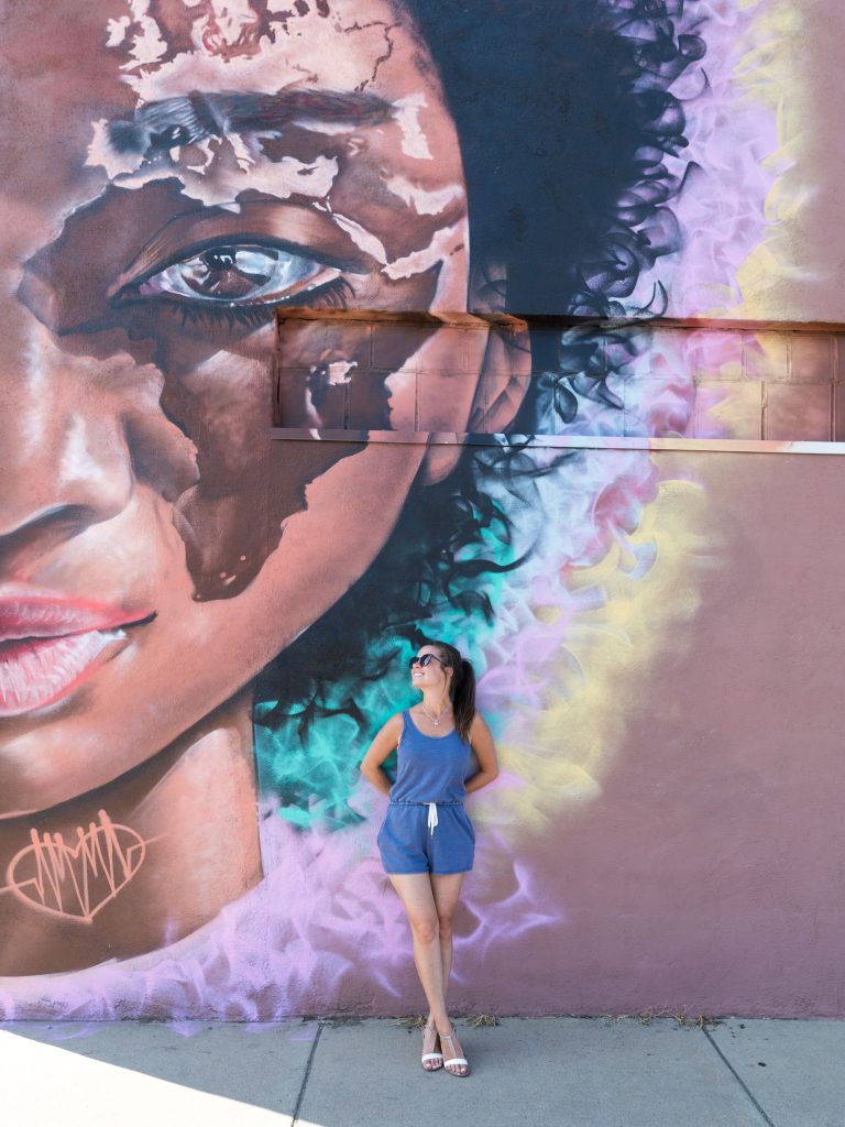 A girl standing in front of street art in Denver, Colorado.