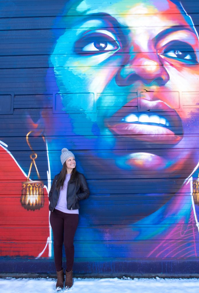 A girl standing in front of colorful street art in Denver.
