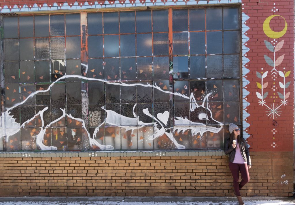 A girl standing in front of street art in Denver.