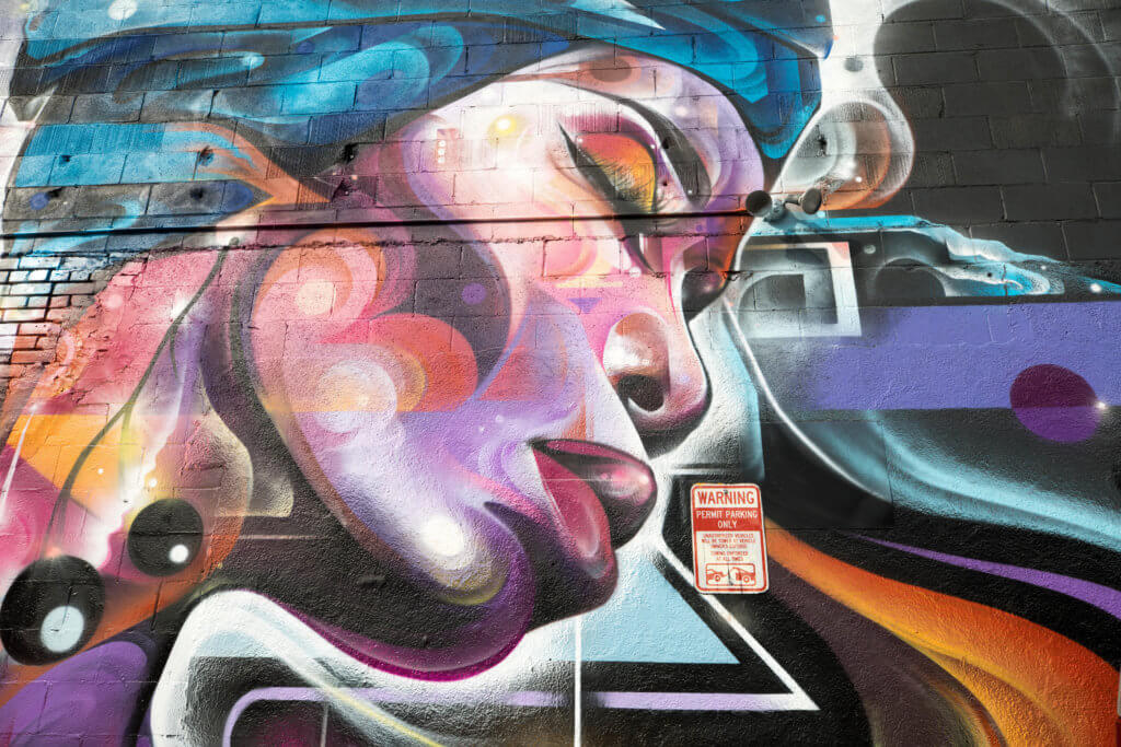 Street art of a colorful woman's face. Discover where to find the best street art in Denver! From memorable murals to colorful characters, here's what you need to know. And for more travel tips and wanderlust inspiration, follow The Scenic Suitcase on Pinterest!