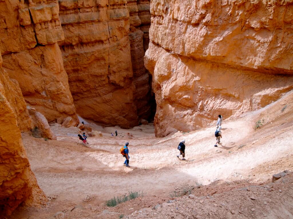 People hiking down a trail in Bryce Canyon. Discover some of the most beautiful places in the American Southwest. Awe-inspiring destinations and what you shouldn't miss on your next road trip! And for more travel tips and wanderlust inspiration, follow The Scenic Suitcase on Pinterest!
