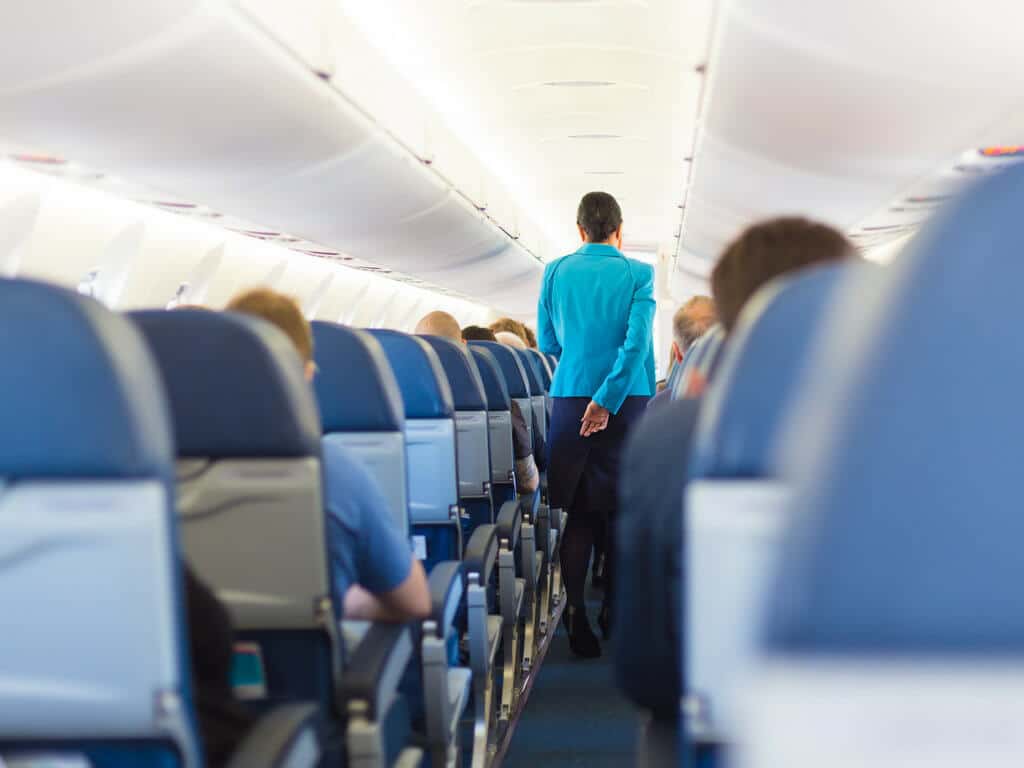 An aisle on an airplane. Use these secret travel hacks for better flights, hotels, and cruises! Along with tips on how to avoid lines, pick the best travel destinations, and more! And for more travel tips and wanderlust inspiration, follow The Scenic Suitcase on Pinterest!