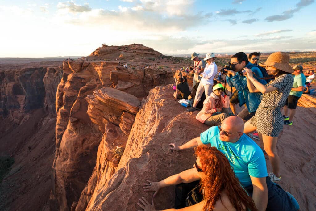 A massive crowd on the edge of the cliff to watch sunset over Horseshoe Bend. Discover some of the most beautiful places in the American Southwest. Awe-inspiring destinations and what you shouldn't miss on your next road trip! And for more travel tips and wanderlust inspiration, follow The Scenic Suitcase on Pinterest!