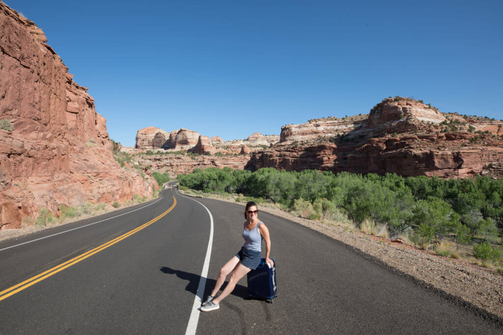 Girl sitting on a suitcase near the side of the road on Highway 12. Discover some of the most beautiful places in the American Southwest. Awe-inspiring destinations and what you shouldn't miss on your next road trip! And for more travel tips and wanderlust inspiration, follow The Scenic Suitcase on Pinterest!