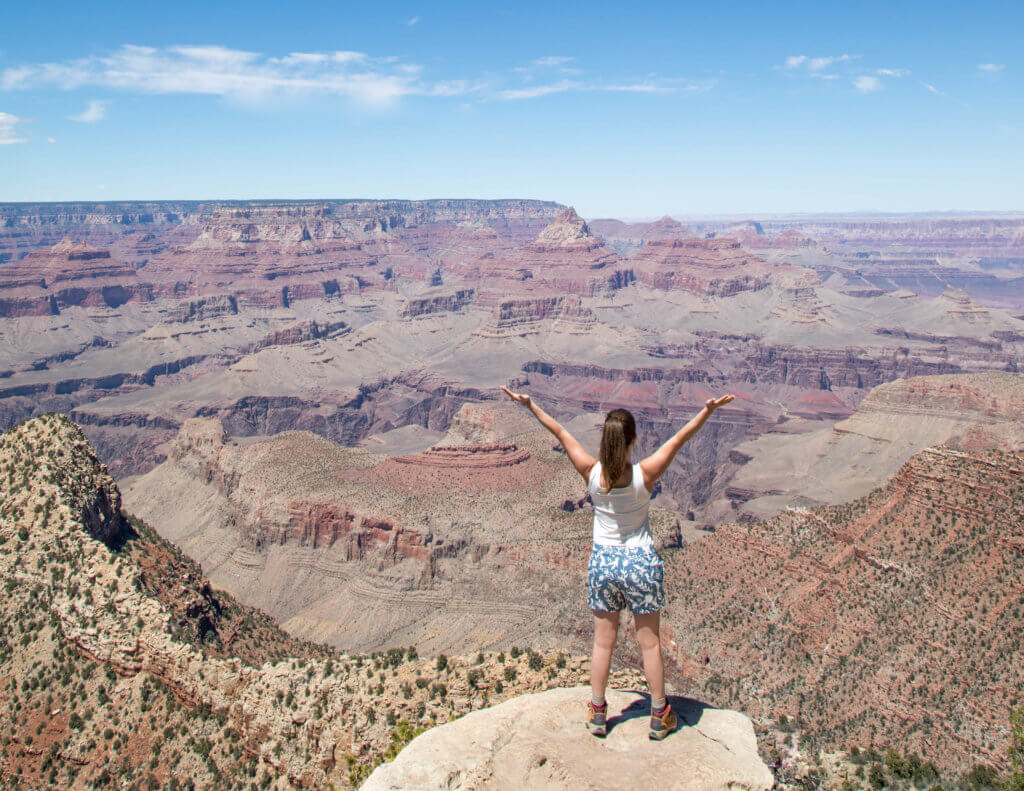 Girl triumphantly holding her arms in the air at the top of the Grand Canyon. Discover 10 reasons to travel solo, and why seeing the world on your own will rock your socks off. Surprising perks, life-changing opportunities, and more! And for additional travel tips and wanderlust inspiration, follow The Scenic Suitcase on Pinterest!