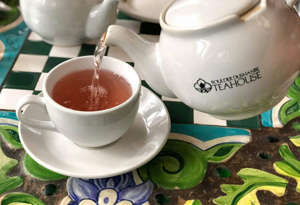 A teapot pouring tea on a decorative floral table top. Discover the most stunning, offbeat, and unique places in Colorado. Including cliff diving dinner entertainment, haunted hotels, towering dunes, and more! And for additional travel tips and wanderlust inspiration, follow The Scenic Suitcase on Pinterest!