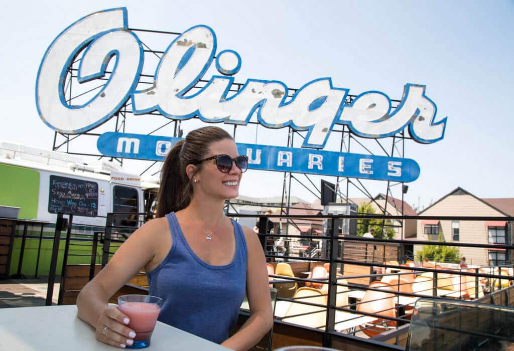 A girl smiling as she drinks a cocktail at the Linger rooftop bar. Discover the most stunning, offbeat, and unique places in Colorado. Including cliff diving dinner entertainment, haunted hotels, towering dunes, and more! And for additional travel tips and wanderlust inspiration, follow The Scenic Suitcase on Pinterest!