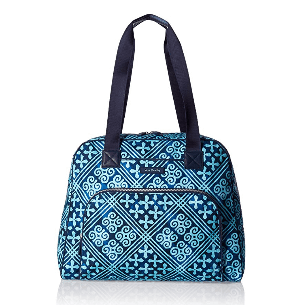 A blue carry on bag with a tile design. Discover the top 10 travel essentials every globetrotter needs. These helpful (and sometimes surprising) accessories will transform the way you travel! And for more travel tips and wanderlust inspiration, follow The Scenic Suitcase on Pinterest!