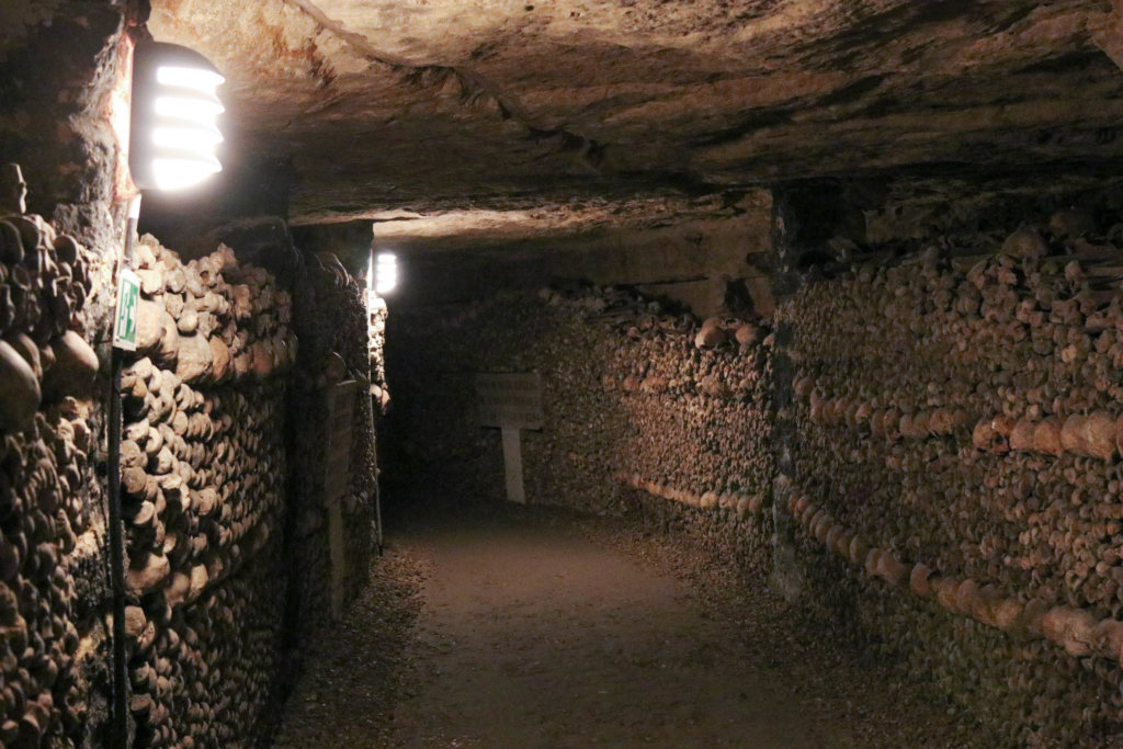 Dark underground passage lined with walls of human bones. Learn the best tips for visiting the Paris catacombs. How to avoid insanely long lines, and what to expect when you get there! And for more travel tips and wanderlust inspiration follow The Scenic Suitcase on Pinterest!