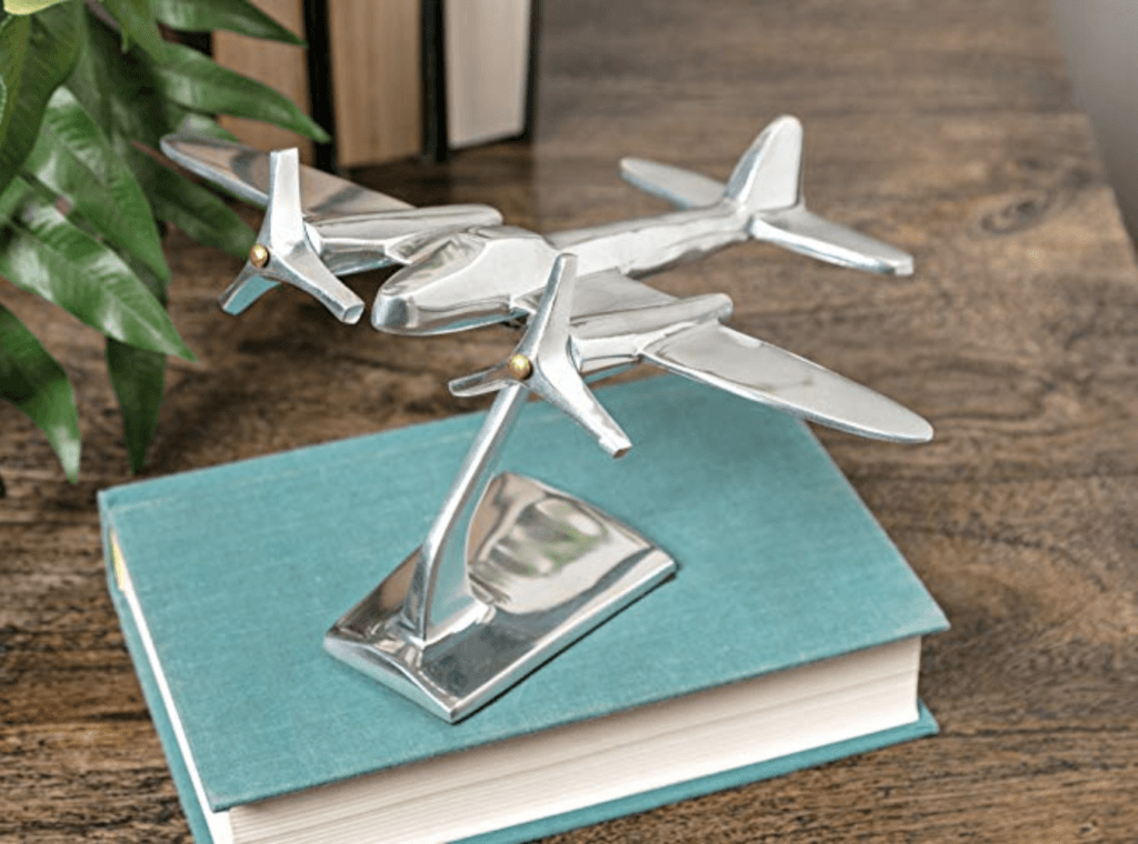 A silver airplane statue sitting on top of a teal book on a desk. Stylish, afforable, and fun travel inspired home decor that's perfect for anyone with a serious case of wanderlust. Find that perfect accent for your home! And for more travel tips and wanderlust inspiration, follow The Scenic Suitcase on Pinterest!