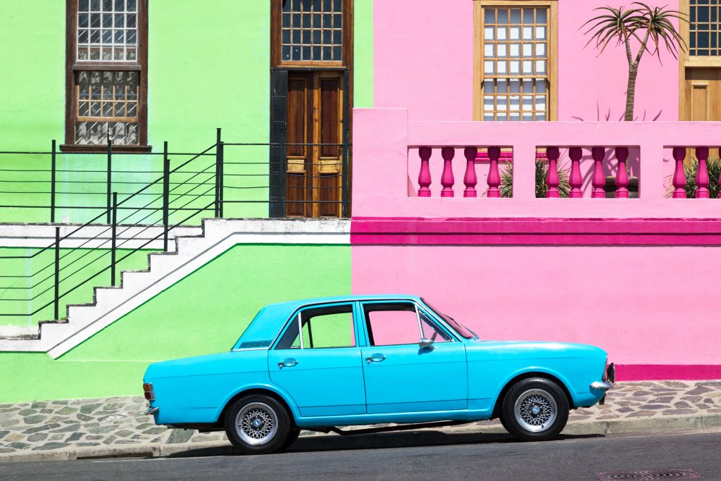 A blue car in front of green and pink buildings. See the most picture perfect moments of 2018. From London to Cape Town to Las Vegas and more, see what you can't miss in these incredible destinations! And for more travel tips and wanderlust inspiration, follow The Scenic Suitcase on Pinterest!