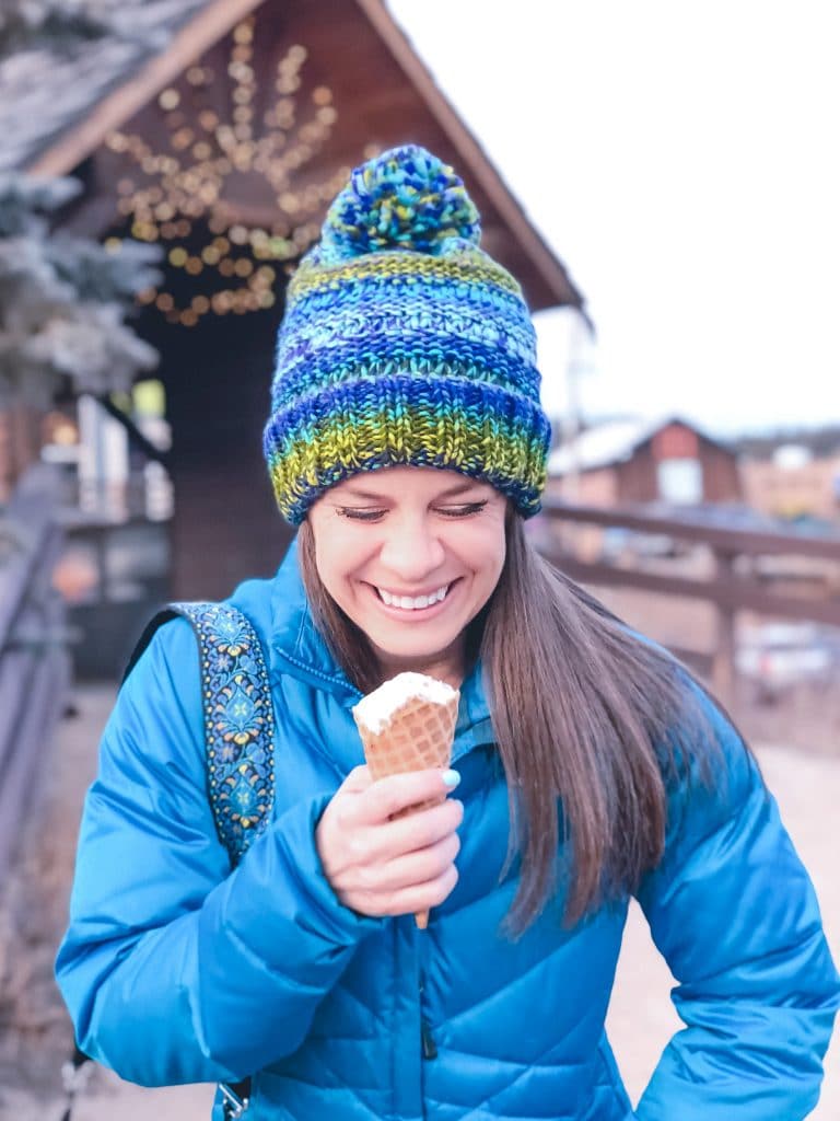 A girl in a winter coat and hat laughing as she eats an ice cream cone. The ultimate winter packing guide with a complete list of items you need for winter travel. Everything you need to stay warm and toasty! And for more travel tips and wanderlust inspiration, follow The Scenic Suitcase on Pinterest!