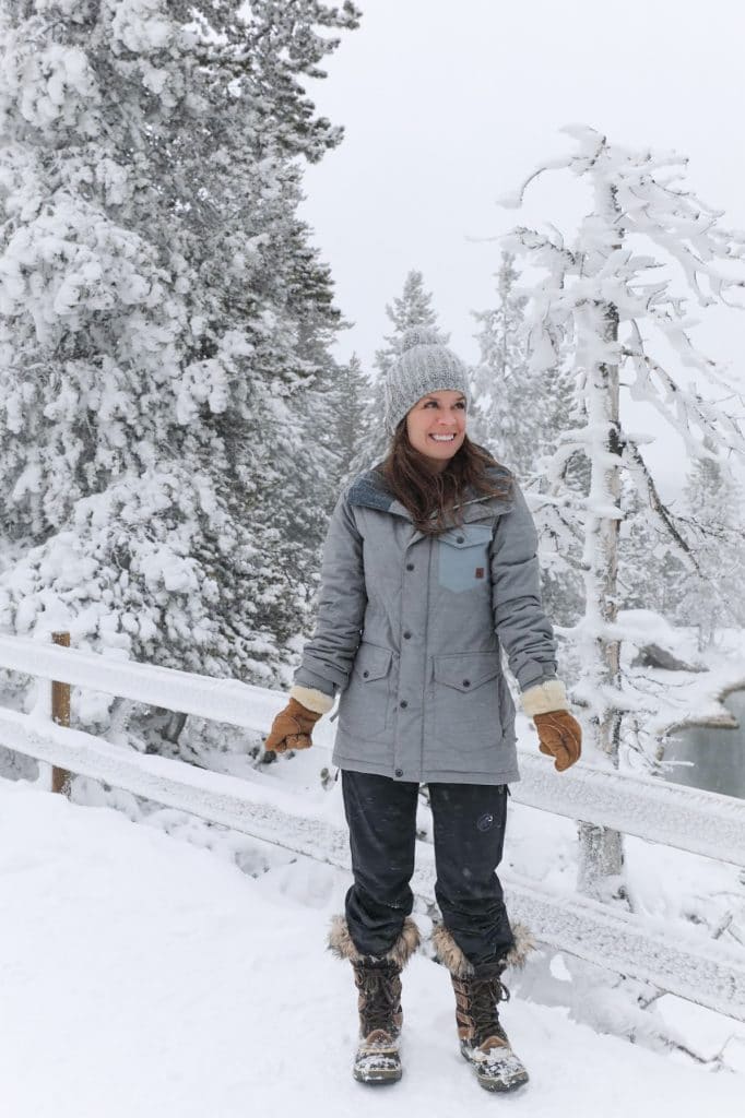 Girl wearing gray snow coat and hat in the middle of a winter wonderland. The ultimate winter packing guide with a complete list of items you need for winter travel. Everything you need to stay warm and toasty! And for more travel tips and wanderlust inspiration, follow The Scenic Suitcase on Pinterest!