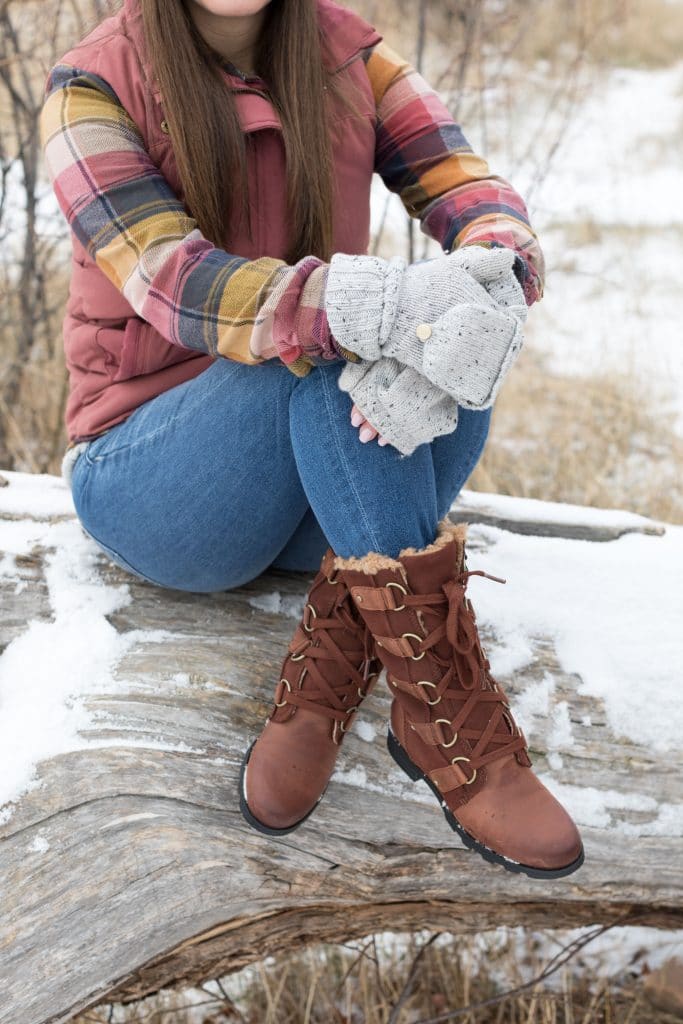 Close-up of Sorel boots on a girl sitting on a tree stump. The ultimate winter packing guide with a complete list of items you need for winter travel. Everything you need to stay warm and toasty! And for more travel tips and wanderlust inspiration, follow The Scenic Suitcase on Pinterest!