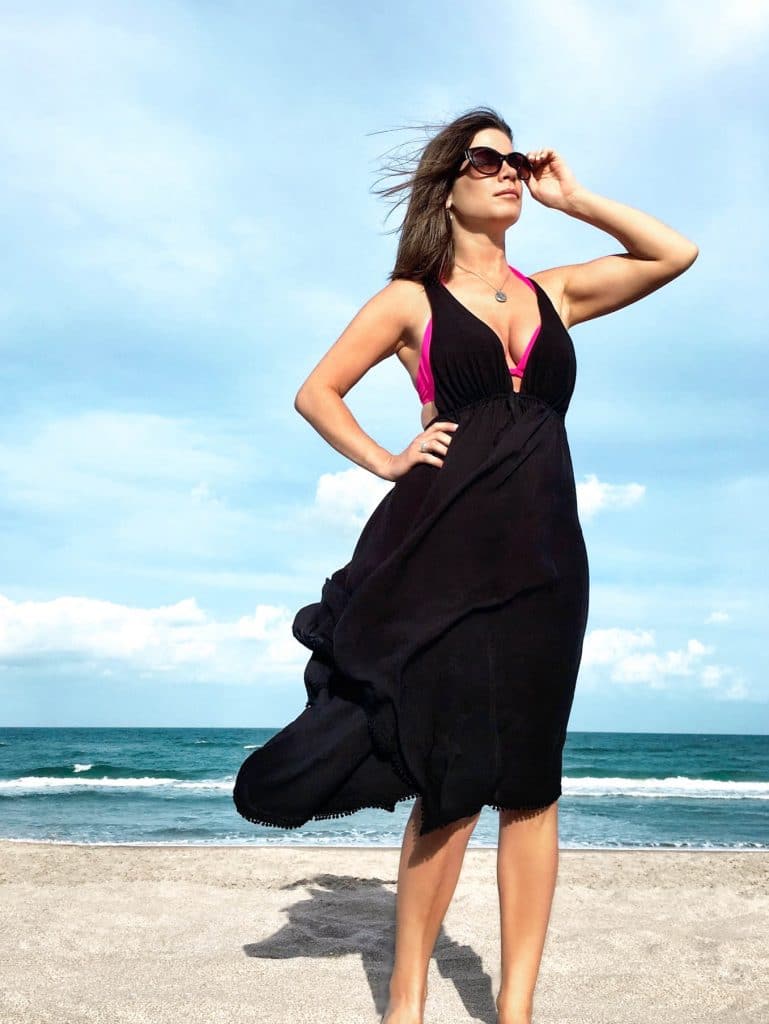 Girl standing in a swimsuit and black swimsuit cover up on the beach. This complete beach packing guide includes everything you need for your next tropical vacation. Plus, suggestions on products you'll love on your travels! And for more travel tips follow The Scenic Suitcase on Pinterest!