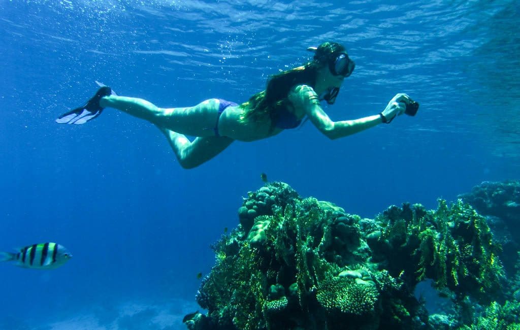 Girl snorkeling and holding a camera underwater. This complete beach packing guide includes everything you need for your next tropical vacation. Plus, suggestions on products you'll love on your travels! And for more travel tips follow The Scenic Suitcase on Pinterest!