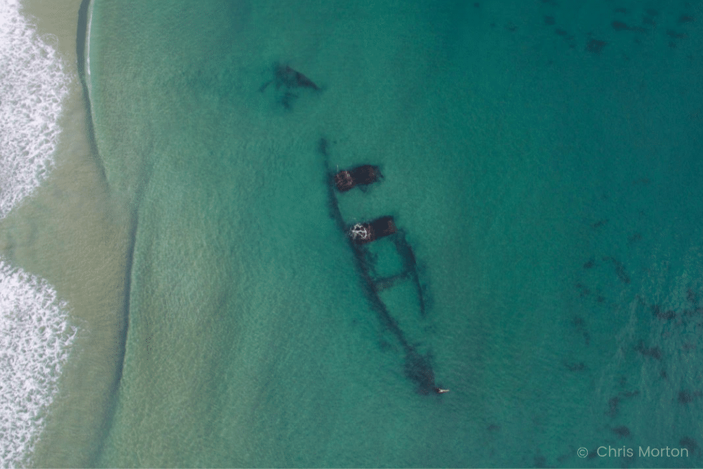 An aerial shot of a shipwreck underneath the ocean. Drone Photography 101 includes everything you need to know for impressive aerial images and jaw-dropping video footage. From beginner to advanced!